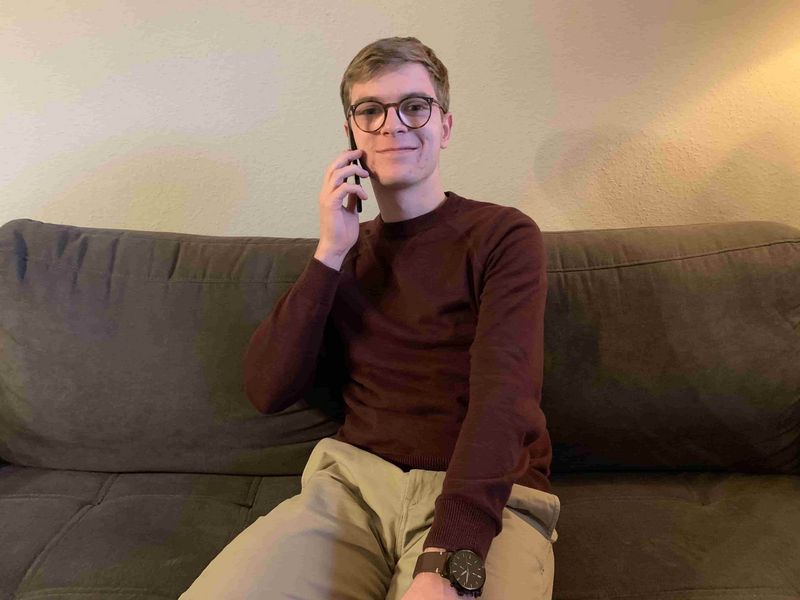 Junger Mann mit Brille telefoniert mit einem Smartphone