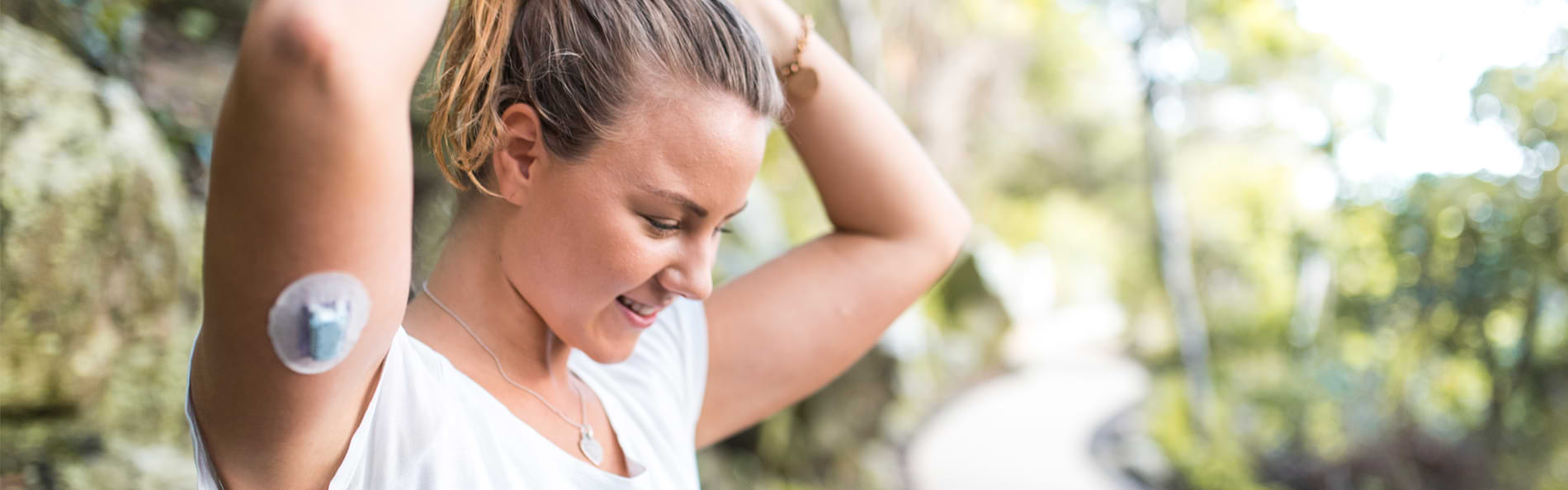 Eine junge Frau mit Diabetespflaster bereitet sich auf einen Lauf vor. 