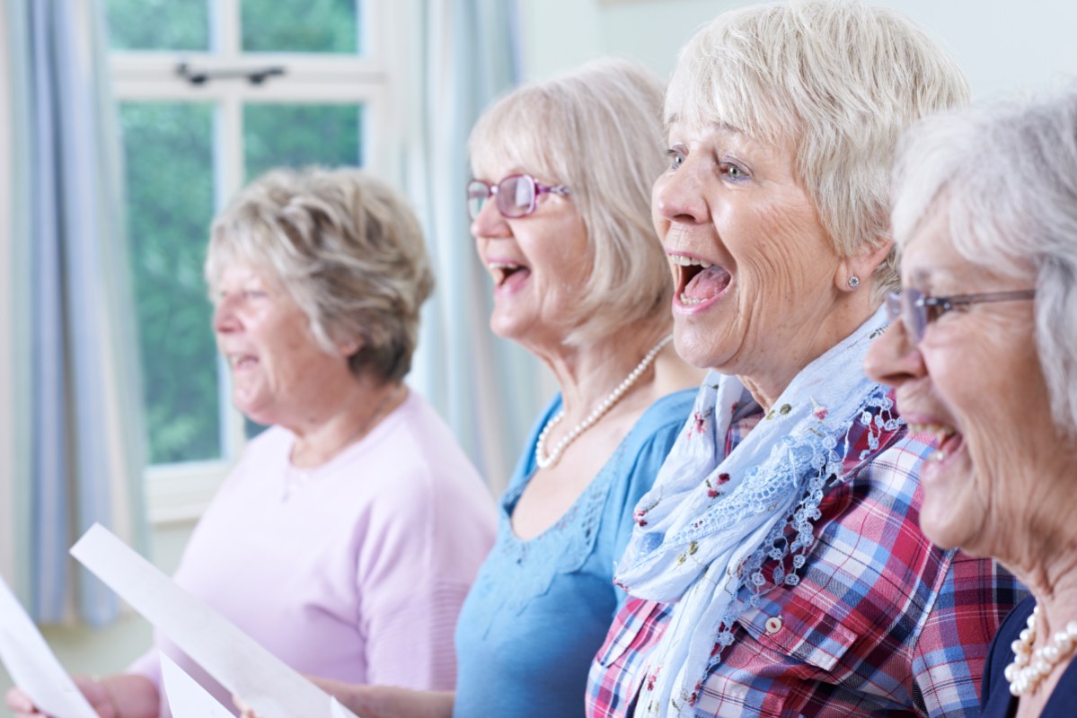 Vier ältere Frauen mit Notenblättern in der Hand singen