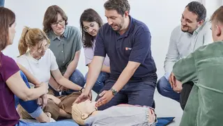 Ausbilder der Malteser Ersten-Hilfe-Kurse erklärt Notfallmaßnahmen an einem Dummy.