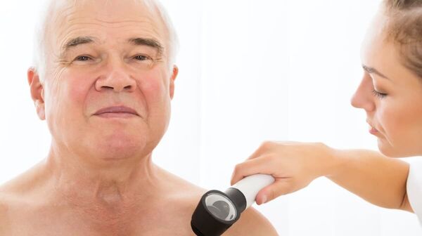 Eine Ärztin führt eine Hautuntersuchung bei einem älteren Mann durch.