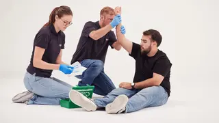 Zwei junge Erwachsene üben Erste-Hilfe-Grundlagen an einem jungen Mann.