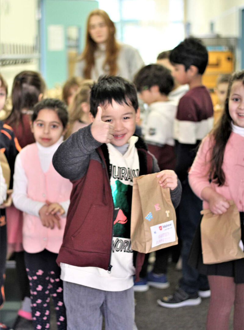 Kinder in einem Klassenzimmer mit braunen Papiertüten