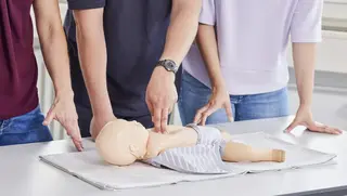 Erste-Hilfe-Maßnahmen für Kindernotfälle werden an einer Babypuppe erprobt.