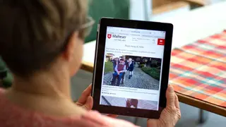 Frau schaut sich das Online-Magazin "dabei" auf einem Tablet an.