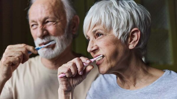 Ein älteres Paar putzt gemeinsam die Zähne.