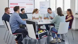 Sieben junge Erwachsene sitzen beim Malteser Erste-Hilfe-Kurs für Fortbildungszwecke zusammen.