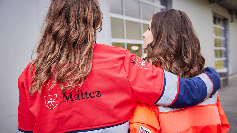 Zwei Frauen aus dem Malteser Volunteers-Programm umarmen sich. 
