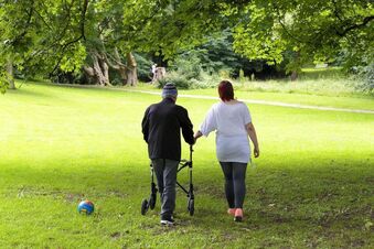 Hospizpatient mit Angehöriger gehen im Park spazieren