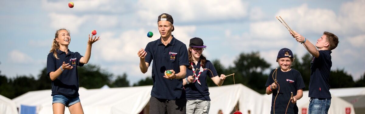 Jugendliche jonglieren auf einer Wiese.