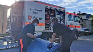 Malteser Mitarbeiter im Katastrophenschutz packen zusammen.