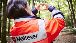 Malter Helferin formt mit den Händen ein Herz