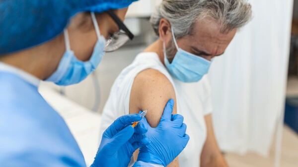 Eine Ärztin führt bei einem älteren Mann eine Impfung durch.
