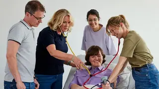 Schüler eines Ausbildungskurses üben am Krankenbett das Blutdruckmessen.