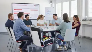 Sieben junge Erwachsene sitzen beim Malteser Erste-Hilfe-Kurs für Fortbildungszwecke zusammen.