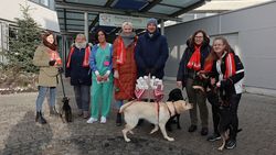 Ehrenamtliche Malteser mit Hunden übergeben Korb mit Schokonikoläusen an Mitarbeiterin des Klinikums Freising